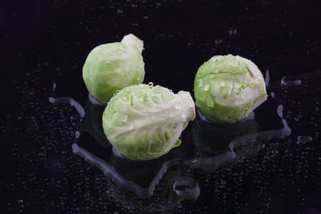 Three brussels sprouts with water on blackの写真素材