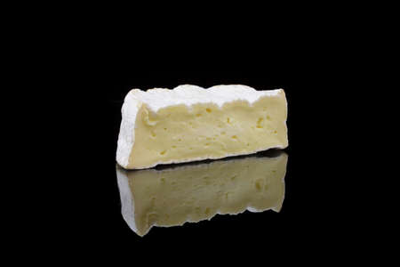 a piece of camembert cheese on black backgroundの写真素材