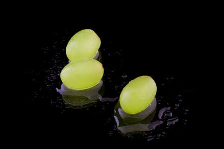Three grapes with water on black backgroundの写真素材