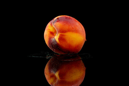 a peach with water on black background