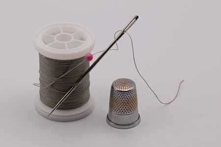 For sewing, spool of thread, needle, and thimble on a light gray backgroundの写真素材