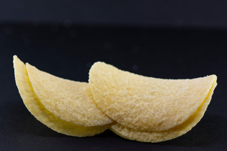 Potato chips with salt, cheese and garlic on a black background