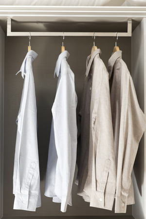 row of white and grey shirts hanging in wardrobeの写真素材