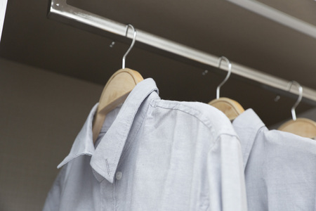 row of white and grey shirts hanging in wardrobeの写真素材