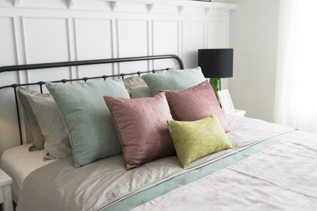Modern furniture in a cozy minimalist bedroom with pastel pink and green accents pillows.の写真素材