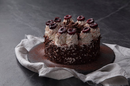 Close-up chocolate cake with sugar icing and cherry decoration.