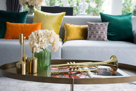 colorful and stylish living room with flower vase and gold trumpet on table.