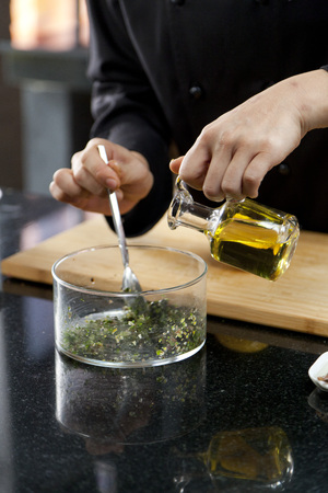 The chef cooking food, pouring olive oil into glass bowl.の写真素材