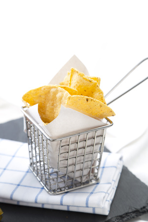 Crispy potato chips in a metal basket on black stone board on a table.の写真素材