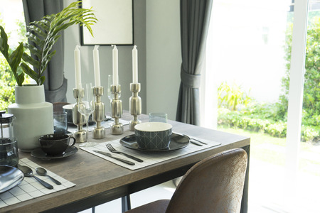 Black and white plate setting on wooden dining table at homeの写真素材