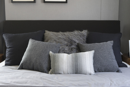 Bed with white and grey linens and a lot of pillows.の写真素材