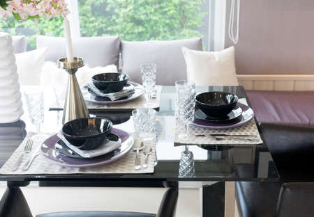 dining wooden table and comfortable chairs in modern home with elegant table settingの写真素材