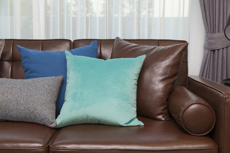 Blue and gray pillows on leather sofa in modern living roomの写真素材