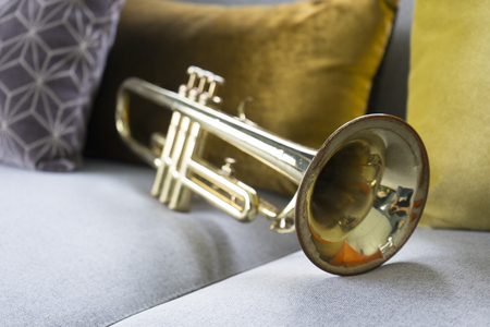 old golden trumpet lying on grey sofaの写真素材