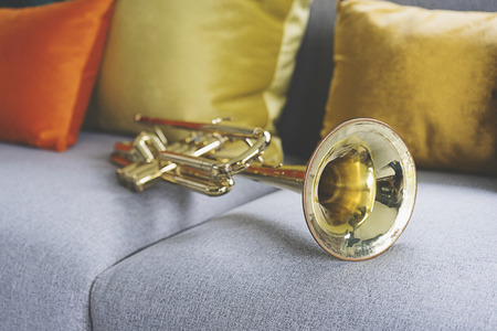old golden trumpet lying on grey sofaの写真素材