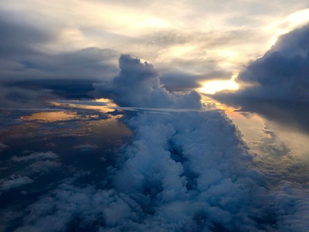 Sunset sky and an ocean as seen through window of airplane flying above the clouds in the sky.の写真素材