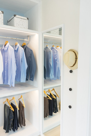 white modern wardrobe with black and blue cloth hanging.の写真素材
