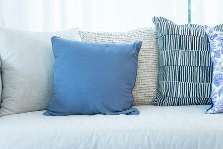 close up of set of white, blue and grey pillows on white Sofa