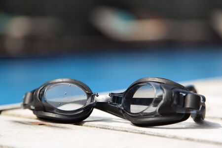 swimming goggles  on the deck beside the poolの写真素材