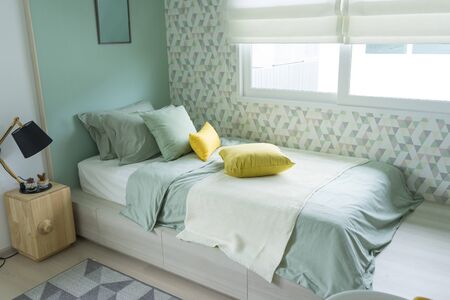 Contemporary teen bedroom with green pillow and modern side table lamp.の写真素材