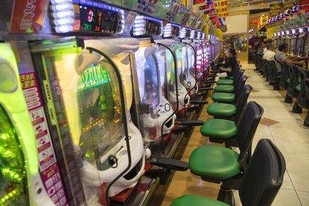 Row of pachinko machines with colorful neon lights.のeditorial素材