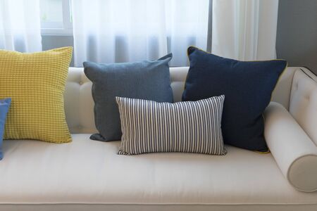 Interior of minimalistic living room with white sofa and yellow, blue cushion.の写真素材