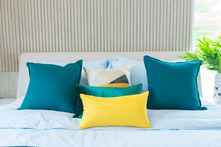 Yellow and green pillow on bed in modern interior bedroom.