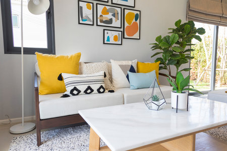 Fashionable living room interior with yellow and blue accents. Green plant pot and picture frame on...