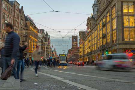people walking in Dam Square with tram running in the background in Amsterdam, Netherlandsのeditorial素材