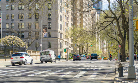 Cars driving on 5th Ave, New York past pedestrians and commercial shops