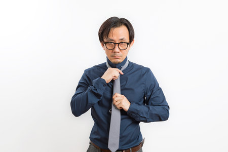 Asian businessman fitting up blue suit and necktie on white background. Getting dress for conference.の写真素材