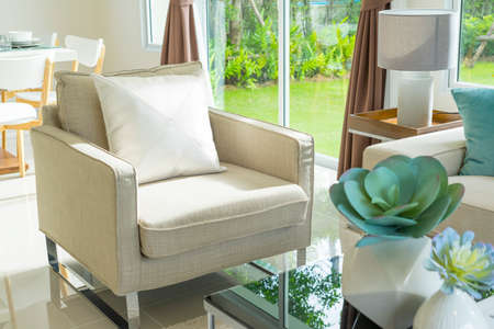 White sofa and yellow and blue pillows with a green leave vase on side table in living cornerの写真素材