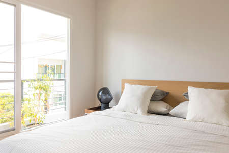 Minimal contemporary style bedroom with white fabric bed set and side table lamp.の写真素材