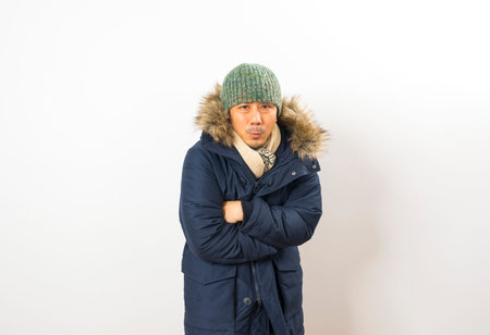 Handsome asian man dressed with winter clothing, hat and scarf isolated on white backgroundの写真素材