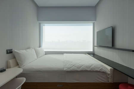 Cozy small bedroom in apartment or condominium. Little bed stay near window on a hotel.のeditorial素材