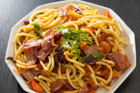 Spaghetti alla Amatriciana with bacon, tomatoes and dried chili on black wood table.の写真素材