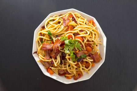 Spaghetti alla Amatriciana with bacon, tomatoes and dried chili on black wood table.の写真素材