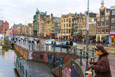 people walking on Damrak avenue at evening light in Amsterdam, Netherlandsのeditorial素材