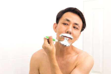 handsome asian man trying shave beard in bathroom.の写真素材