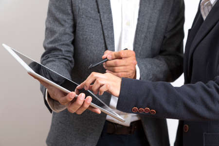 Businessman and woman holding tablet while discussing marketing plan standing on white background.の写真素材