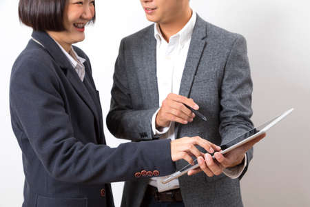 Businessman and woman holding tablet while discussing marketing plan standing on white background.の写真素材