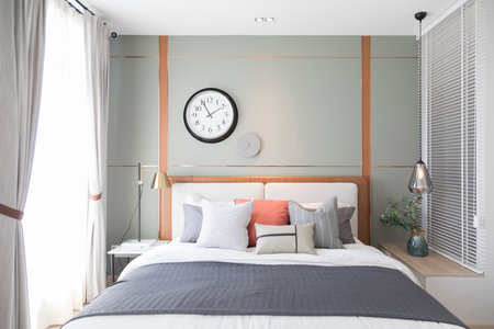 Stylish interior of modern bedroom. White, grey and pastel orange design pillow setting in cozy...