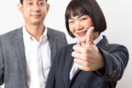 Happy business man and woman showing thumb up over white background.の写真素材