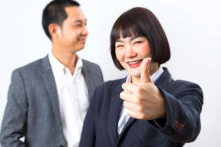Happy business man and woman showing thumb up over white background.の写真素材