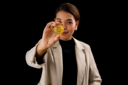 Successful Asian businesswoman standing over black background holding bitcoin money.の写真素材