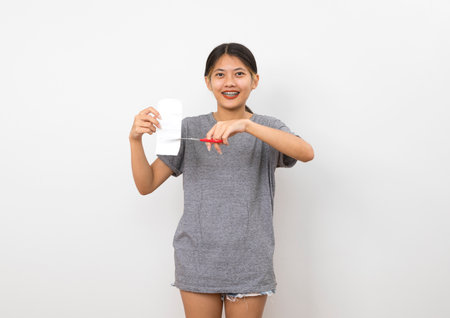 young asian woman wisely manage household expense by cutting the bill on white background.の写真素材