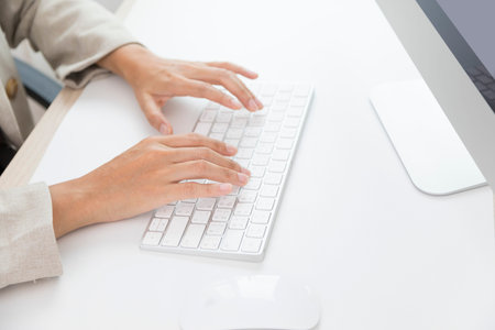 Manager typing on computer keyboard at wooden desk.  Close up woman hands on keyboard.