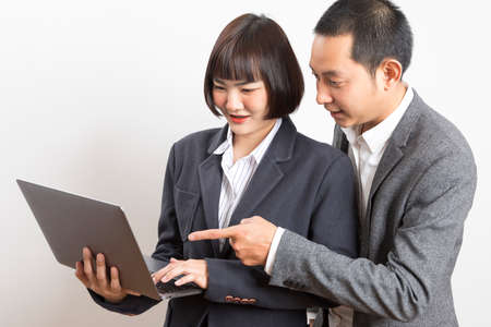 Asian businesswoman and businessman holding computer standing on white background.の写真素材