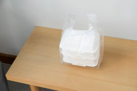 Plastic bags and food containers on wood table. Food delivery service.