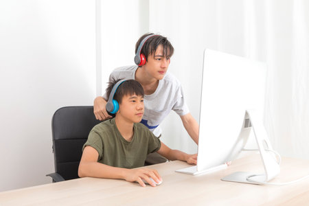 Two multiethnic teenage boys with headphone have fun with computer games at home.